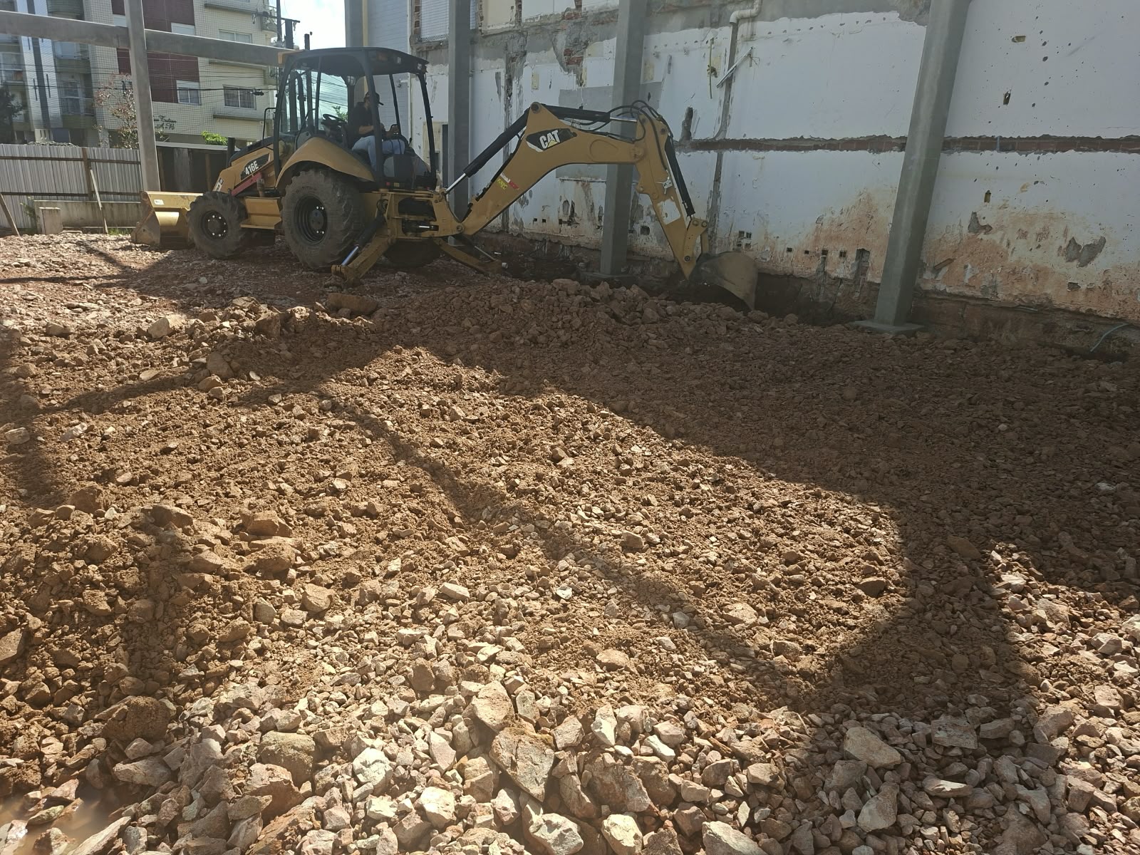 Retroescavadeira escavando junto à fundação de uma construção